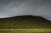 UK, Schottland, Gewitterwolken über grünem Hügel