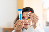 Chemist holding test tube and molecular model, focus on foreground