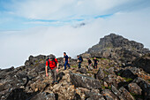 Wanderer tauchen über den Wolken nahe dem Gipfel des Sgurr Nan Eag auf, einem der Gipfel der Black Cuillin; Isle of Skye, Schottland.