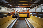 A Woman Sits On The Seat Of A Boat Taxi; Venice, Italy