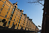 A Brown Brick Building Along A Canal Under A Blue Sky; Hamburg, Germany