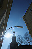 Ein Kirchturm mit einer Sonnenfackel am blauen Himmel; Hamburg, Deutschland