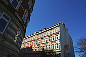 Ein Wohnhaus mit Graffiti an der Seite und blauem Himmel; Hamburg, Deutschland.