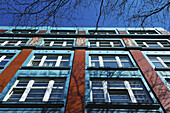 Niedriger Blickwinkel auf die Fassade eines Gebäudes mit Fenstern vor blauem Himmel; Hamburg, Deutschland