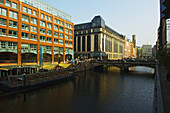 Eine Straßenbrücke über den Fluss und Gebäude entlang des Flusses; Hamburg, Deutschland