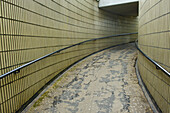 Ein gebogener Gehweg mit Geländer zwischen zwei Backsteinmauern; London, England.