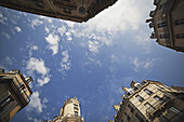 Niedriger Blickwinkel auf die Spitzen verschiedener Gebäude vor einem blauen Himmel mit Wolken; Paris, Frankreich.