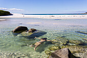 Eine junge Frau schwimmt am Strand der Feuerbucht; Tasmanien, Australien.