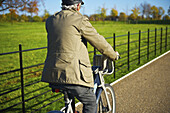Ein Mann fährt mit seinem Fahrrad auf einem Kiesweg im Hyde Park; London, England