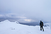 Mann wandert auf dem Beinn Dorain bei verschneiten, winterlichen Bedingungen in der Nähe von Bridge Of Orchy; Argyll und Bute, Schottland.