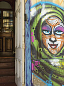 Buntes Gemälde eines menschlichen Gesichts an einer Wohnhauswand; Valparaiso, Chile