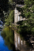 Beschaulicher Kanal mit Spiegelung eines Gebäudes und Bäumen; Yorkshire, England
