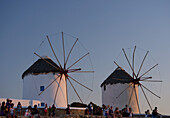 People Watching The Sunset Beneath Old Windmills; Mykonos Town, Mykonos, Cyclades, Greek Islands, Greece