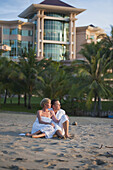 Ein Paar, das am Strand des Empire Hotel und Country Club sitzt; Bandar Seri Begawan, Brunei.