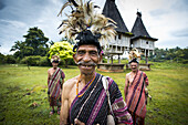 Gruppe von Männern in traditioneller Kleidung mit heiligen Häusern im Hintergrund; Distrikt Lospalmos, Timor-Leste.