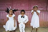 Children Dressed In White Formal Wear Against A Red Wall; Hapai Island, Tonga