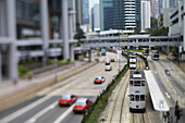 Straßenbahn fährt auf Gleis neben Straße; Hongkong