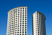 Zwei abgerundete Wohngebäude nebeneinander vor einem blauen Himmel; Genua, Ligurien, Italien.