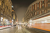Bewegungsunschärfe der Straßenbahn auf der Straße bei Nacht; Mailand, Lombardei, Italien