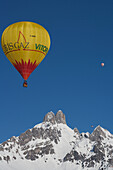 Hot Air Balloons Floating High Above Snowy Bishop's Hat Mountain Peaks During The Ski Resort's Annual Hot Air Balloon Festival; Filzmoos, Austria