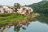 Ruhiger Fluss mit Häusern entlang der Wasserkante in einem kleinen Dorf bei Wuyuan; Provinz Jiangxi, China
