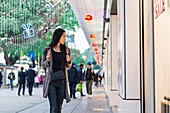 A Young Woman Window Shopping At The Retail Shops Along The Street, Kowloon; Hong Kong, China