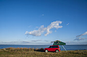 Ein rotes Fahrzeug mit hochgelegtem Zelt entlang der Küste; Laguna De Rocha, Uruguay