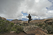 Ein Mann springt auf einen Felsen und blickt auf die wunderschöne Landschaft des Toro Toro Nationalparks; Bolivien.