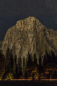 A Vehicle Drives Along Northside Drive In Front Of El Capitan At Night In Yosemite Valley, Yosemite National Park; California, United States Of America