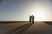 Silhouetten von Wüstenführer und Tourist bei Sonnenuntergang; Merzouga, Marokko