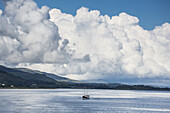 Wogende Wolken und ein Boot im Meer vor der Küste; Isle Of Mull, Argyll And Bute, Schottland