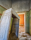 Sand in den Räumen eines farbenfrohen und verlassenen Hauses; Kolmanskop, Namibia