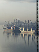 Morgennebel im Hafen mit Schiffen, die sich im Wasser spiegeln; Dar Es Salaam, Tansania.