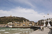 High Tide At La Concha Bay, With The Promenade Leading Towards The Old Town And Fortress; San Sebastian, Spain