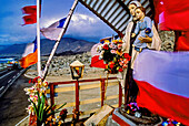Flags and statuary decorate a colorful roadside altar in a desolate region of northern Chile. Shrines or animitas are a common tradition of memorials that mark the site where someone died. People who are not related to the person who was killed can offer a prayer at the animita; in this way, animitas can take the roles of popular saints in the Catholic religion; Pan American Highway, Chile