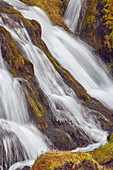 Moosbewachsener Fels und die raue Schönheit des Hafrafell-Wasserfalls in den Bergen bei Stykkisholmur, Halbinsel Snaefellsnes im Westen Islands; Island