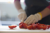 Nahaufnahme eines Arbeiters, der frische Tomaten schneidet
