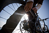 Ein Mann kontrolliert mit den Händen das Rad eines Fahrrads