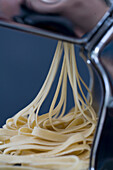 Heap of fresh tagliatelle coming out of a pasta maker