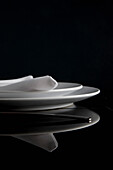 Close up of a place setting with plates and napkin on a glass table