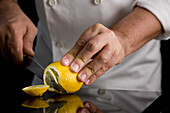 Close up of a chef hands slicing a lemon