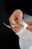 Nahaufnahme eines Kellners, der eine silberne Gabel mit einer weißen Serviette poliert