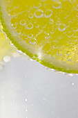 Extreme close up of a slice of lime floating in sparkling water