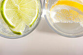 Extreme close up of two glasses of sparkling water with lemon and lime