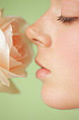 Extreme close up of a young woman profile inhaling a pink rose