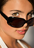 Junge Frau mit dunkler Sonnenbrille, die sie bis zur Nasenspitze heruntergeschoben hat