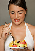 Lächelnde junge Frau isst einen Obstsalat