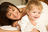 Woman and a toddler hugging and smiling in bed