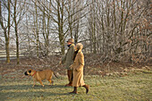 Profile of a mature couple walking with a dog in a park