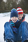 Close up of a boy pushing a friend sitting on sled
